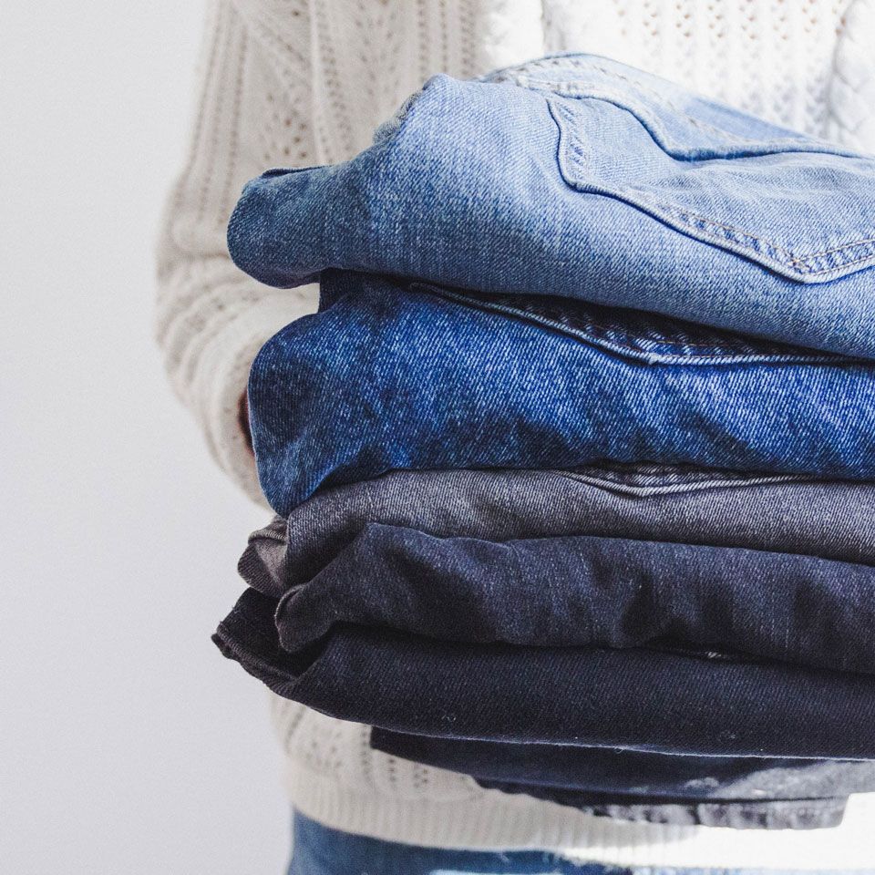 Jeans folded and held by person with white sweater